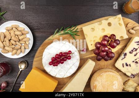 Un assortiment de différents types de fromage aux raisins, tourné à partir de ci-dessus, sur un fond rustique foncé avec une place pour le texte Banque D'Images