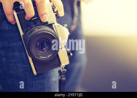 L'homme est maintenant un appareil photo à la main vintage, jeans et chemise Banque D'Images