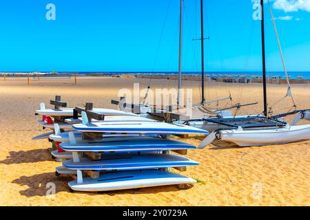 Planches de surf colorées alignées sur une plage de sable. Les planches de surf sont empilées les unes sur les autres Banque D'Images