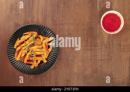 Frites de patates douces rôties au romarin et le ketchup, tourné à partir de ci-dessus, sur un fond de bois rustique foncé, formant une trame avec une place pour le texte Banque D'Images