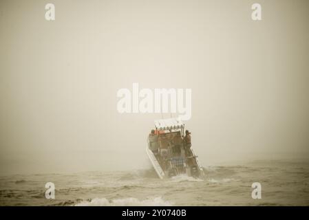 Un bateau à moteur pour la pêche en haute mer se lance dans les vagues et la brume Banque D'Images