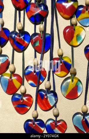 Photo stock de colliers avec des amulettes en verre rondes et en forme de coeur colorées artisanat et souvenirs vertical Banque D'Images