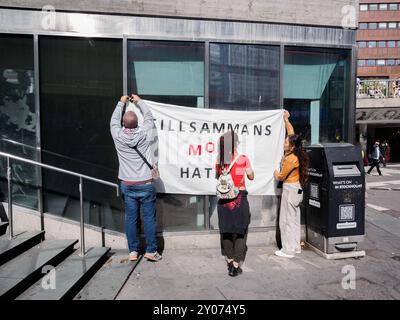 Stockholm, Suède - le 24 août 2024, trois jeunes adultes ont mis une grande bannière avec le message "ensemble contre la haine" en suédois sur un mur pendant un d Banque D'Images