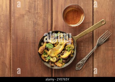 Une photo d'un champignons rustique et olives saute dans une poêle en fonte, avec un verre de vin blanc, tourné à partir de ci-dessus, sur un fond rustique foncé avec copie s Banque D'Images