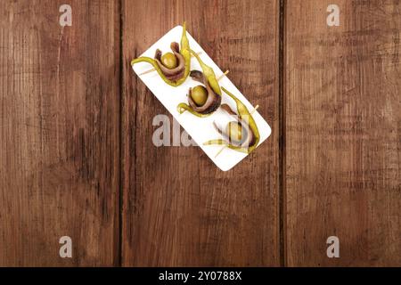 Une photo prise à la verticale d'une gilda, snack-espagnol traditionnel avec une olive, un anchovie, et un poivron mariné, tourné à partir de ci-dessus sur une texture rustique foncé w Banque D'Images