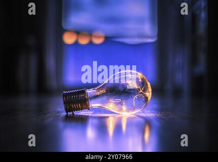 L'ampoule LED repose sur le plancher en bois. Symbole des idées et de l'innovation. Fenêtre et lumière dans l'arrière-plan flou Banque D'Images