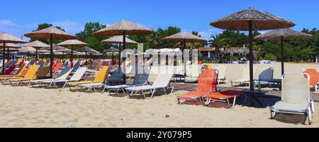 Rangée de parasols en bois et chaise longue au bar de plage de sable, fond de bannière de vacances de mer et de ciel bleu, Grèce, Europe Banque D'Images