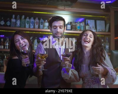 Happy People Group clink verres à vin pour les acclamations dans la boîte de nuit au comptoir. Célébration, amis et concept de fête. Banque D'Images