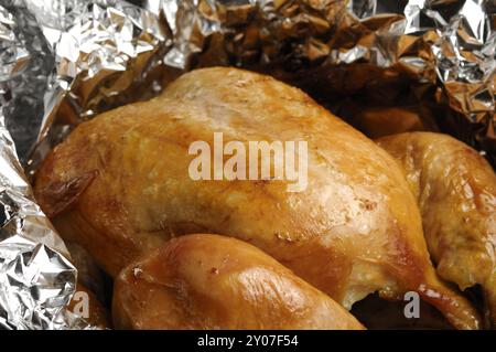 Gros plan d'un poulet rôti aromatisé juteux dans du papier d'aluminium après cuisson au four Art Food Still Life orientation horizontale Banque D'Images