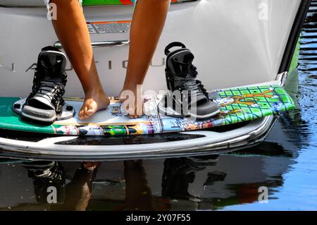 Gros plan des jambes d'une adolescente sur une planche de wakeboard, planche de surf sur un bateau à moteur se préparant au wakeboard Banque D'Images