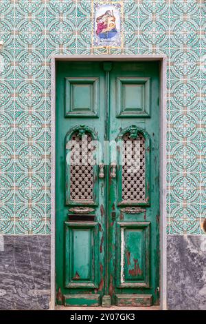 Vieille porte en bois dans un mur de maison décoré avec des azulejos dans la vieille ville d'Olhao, Algarve, Portugal. Vieille porte dans la vieille ville à Olhao, Algarve, Portu Banque D'Images