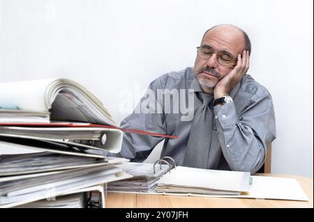 Homme dormant derrière une pile de dossiers Banque D'Images