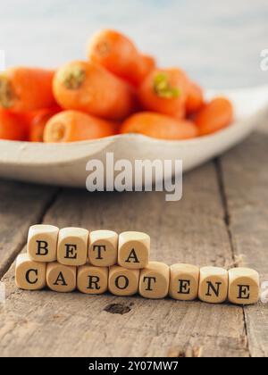 Dés en bois avec les mots du bêta-carotène et les carottes fraîches dans le dos, l'alimentation saine notion Banque D'Images