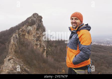 Portrait d'un hipster grimpeur âgé et barbe contre une montagne acérée dans le nord du Caucase. Portrait d'automne d'un grimpeur dans une veste en duvet a Banque D'Images