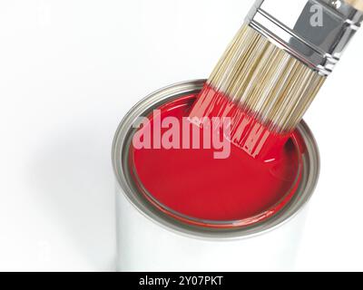 Peinture pinceau trempé dans peut de peinture rouge isolé sur fond blanc Banque D'Images