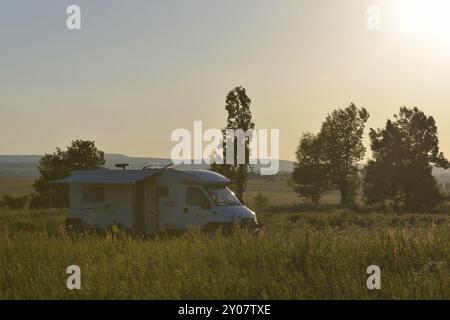 Vacances avec le camping-car. Avec le camping-car dans le soleil du soir en été dans la montagne Banque D'Images