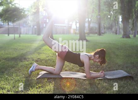 Étirer la femme dans l'exercice extérieur souriant heureux faisant des étirements après la course. Beau modèle de fitness sportif souriant heureux à l'extérieur sur le coucher du soleil d'été Banque D'Images