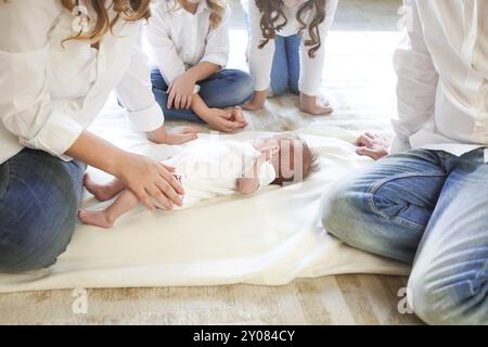 Grande famille avec trois enfants dans le salon blanc. Parents et enfants piquant par bébé nouveau-né. Mère, père et enfants jouant avec le chil nouveau-né Banque D'Images