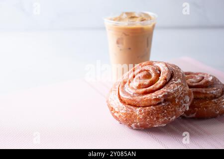 Une vue de quelques petits pains à la cannelle et un café latte, sur le côté droit du cadre. Banque D'Images