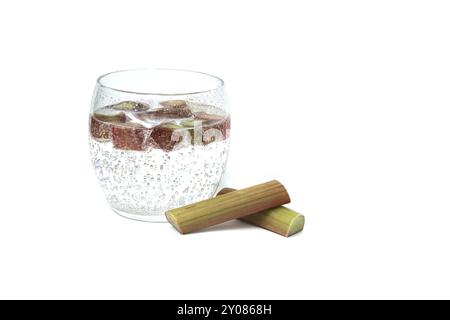 Verre transparent rempli d'eau froide et de plusieurs morceaux de rhubarbe isolé sur fond blanc Banque D'Images