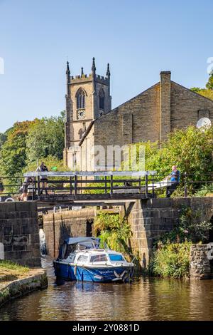 Bateau de plaisance sur le canal de Rochdale alors qu'il passe à travers les écluses sur le canal de Rochdale dans Sowerby Bridge West Yorkshire avec Christ Church Banque D'Images