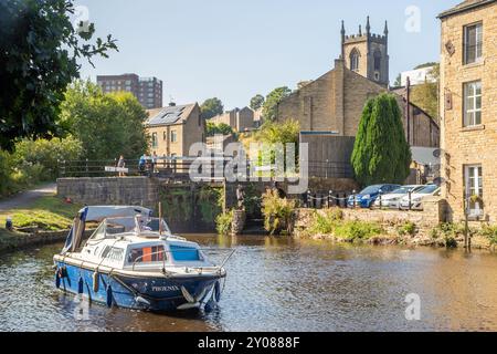 Bateau de plaisance sur le canal de Rochdale alors qu'il passe à travers les écluses sur le canal de Rochdale dans Sowerby Bridge West Yorkshire avec Christ Church Banque D'Images