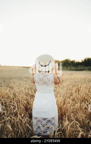 Fille dans le champ de blé, main de fille et épi de blé, coucher de soleil sur le champ. Banque D'Images