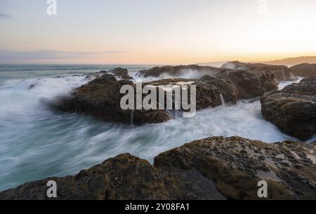 Vagues lavant sur les rochers par la mer, longue exposition, paysage côtier au coucher du soleil, Playa Cocalito, côte Pacifique, péninsule de Nicoya, province de Puntarenas, Banque D'Images