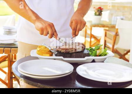 Man cooking steak beaf sur pierres chaudes. Barbecue extérieur Banque D'Images