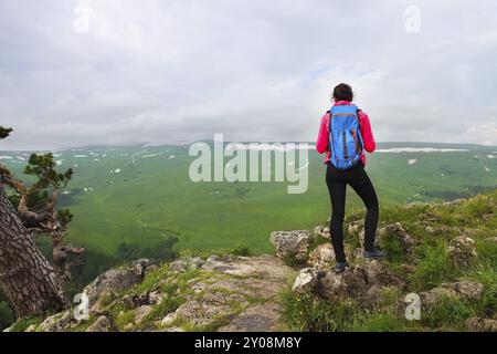 Hiker with backpack se détendre au sommet d'une montagne et profiter de la vallée durant le lever du soleil Banque D'Images