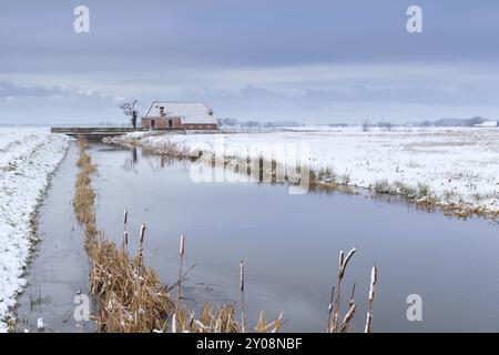 Maison par rivière dans la neige sur les terres agricoles néerlandaises, Hollande Banque D'Images