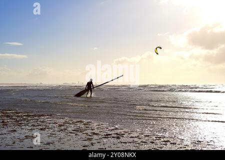 Kitesurfer contre le soleil sur la plage dans les vagues Banque D'Images