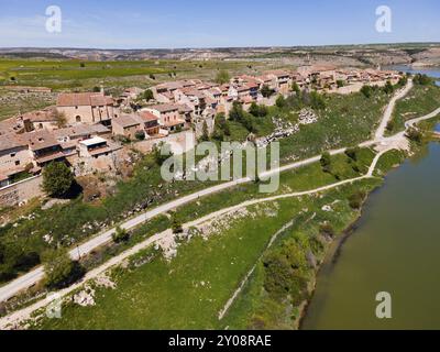 Un village riverain avec des routes traversant les environs verdoyants et courant le long des maisons, vue aérienne, Maderuelo, Rio Riaza, rivière Riaza, Embal Banque D'Images