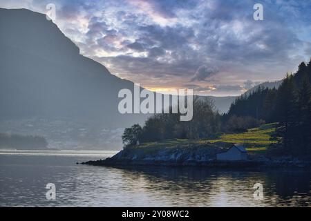 Coucher de soleil sur le fjord avec montagnes en Norvège. Lumière diffuse, rayons du soleil sur un pré. Paysage scandinave Banque D'Images