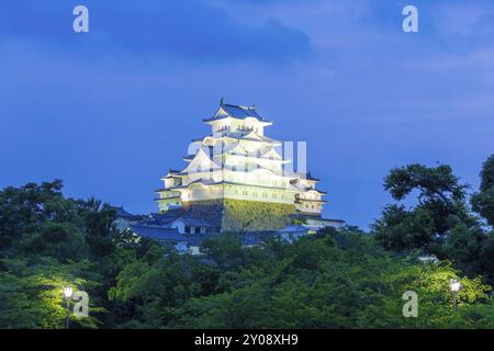 Ciel coloré du coucher de soleil derrière l'ancien château Himeji-JO s'élevant au-dessus de la limite des arbres le soir à Himeji, Japon après 2015 rénovations terminées. Comp. Horizontale Banque D'Images