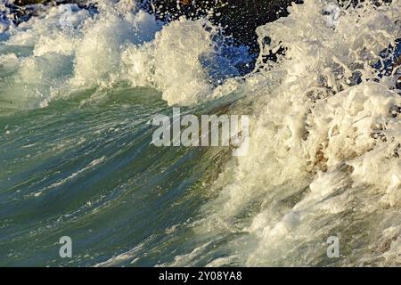 Éclaboussez-vous et faites des gouttes d'eau avec la vague qui s'écrase contre les pierres Banque D'Images