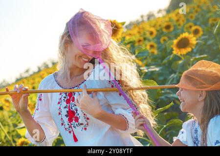 Mère gaie et sa fille jouant dans un champ avec des insectes en soirée d'été Banque D'Images