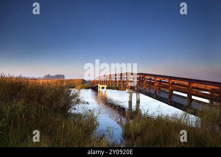 Pont en bois pour vélos à travers la rivière au lever du soleil Banque D'Images