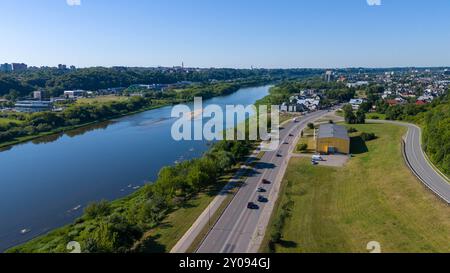 Vue aérienne d'une rivière et d'une ville entourées de forêts verdoyantes denses sous un ciel bleu clair. Banque D'Images