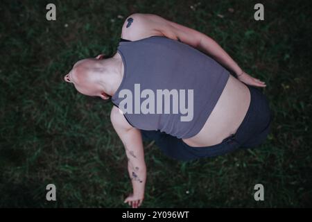 Jeune fille dansant dans le parc mettant en valeur la grâce et le mouvement, vue de dessus de danseuse avec des tatouages et la tête rasée Banque D'Images