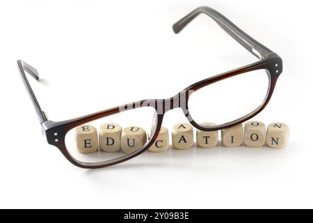 Lunettes et message éducatif écrits dans des blocs de bois, isolés sur fond blanc, symbole, concept Banque D'Images