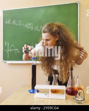 Fille travaillant en laboratoire de chimie avec formule liquide au niveau de la salle de classe Banque D'Images