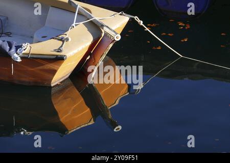 Poupe d'un bateau orange avec gouvernail et le reflet dans l'eau bleu foncé, copie espace Banque D'Images