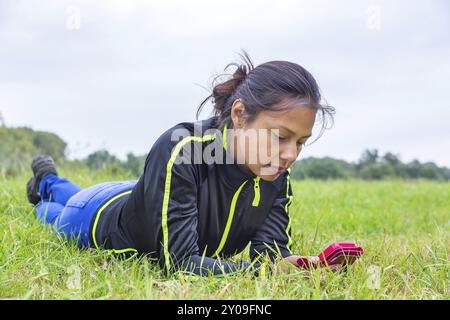 Jeune femme colombienne couché dans la prairie téléphone mobile d'exploitation Banque D'Images