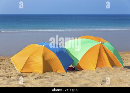 Deux parasols colorés sur la plage par la mer Banque D'Images