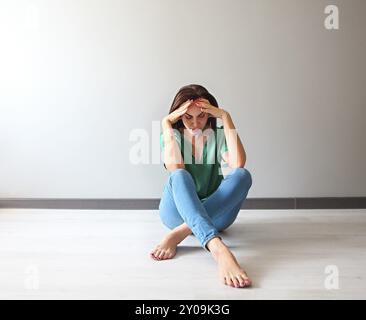 Portrait d'une femme triste à réfléchir sur ses problèmes devant un mur gris Banque D'Images