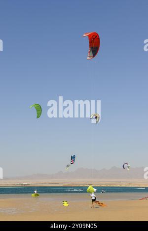 Voile kitesurfer kite surfer kite surfer sur la mer, cinq voiles de cerf-volant dans le ciel bleu sans nuages dans la plage de sable au premier plan de Red Sea Bay, donc Banque D'Images