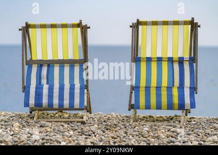 Empty Deck chaises sur la plage de galets à Beer, Devon, Royaume-Uni, regardant Seaton Bay et la chaîne britannique Banque D'Images