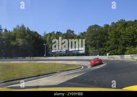 Vue de la voiture de course sur la voiture de sport rouge Porsche Cayman conduit à travers Caracciola-Karrussell section de la piste virage étroit avec pente raide de Nuerburg Banque D'Images