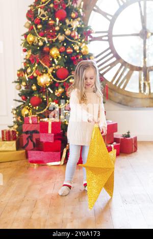 Cute little girl avec l'étoile de Noël avec sapin de Noël sur fond de Banque D'Images